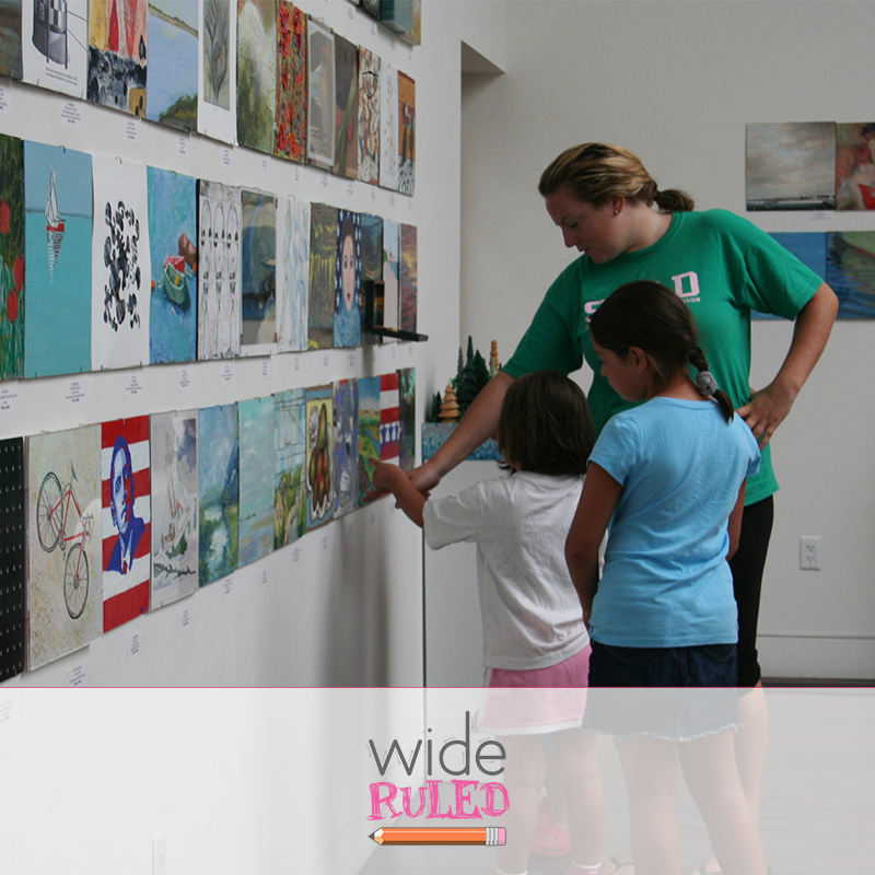 A teacher looks at classroom drawings with students